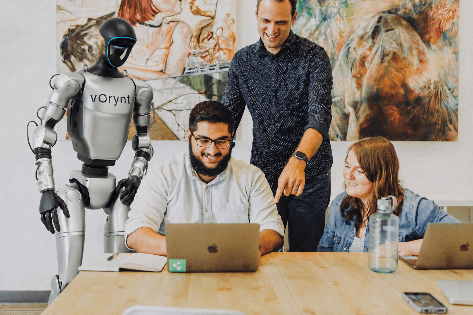 Colleagues gathered around a laptop in a bright office